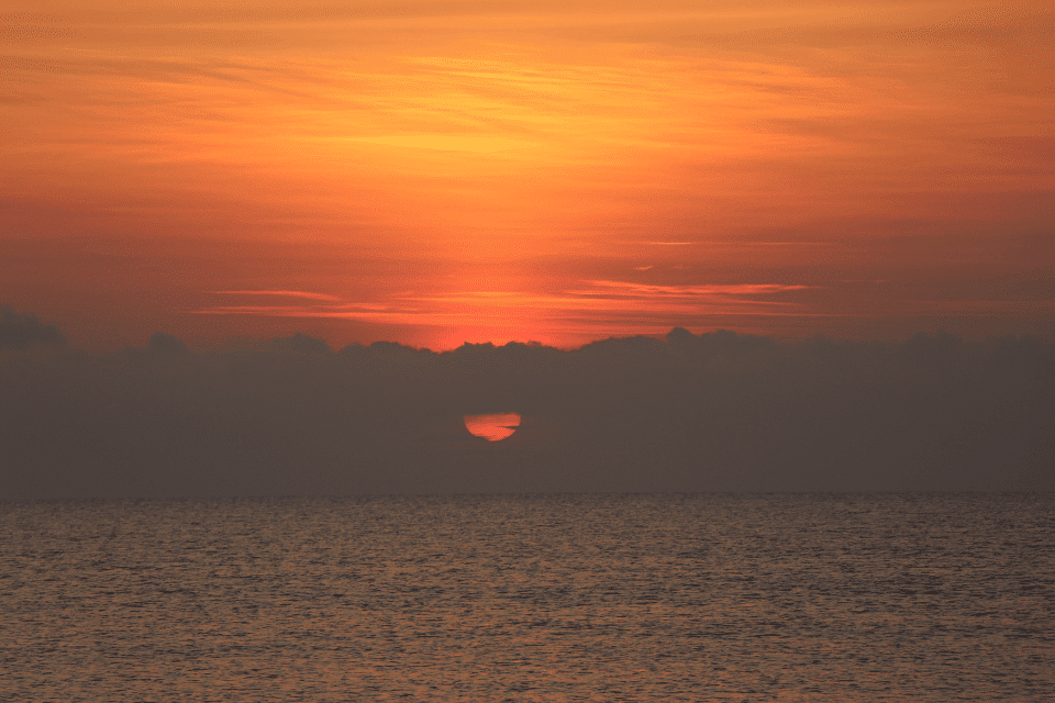 Oranger Horizont – Sonnenaufgang leicht bedeckt mit Blick auf Meer
